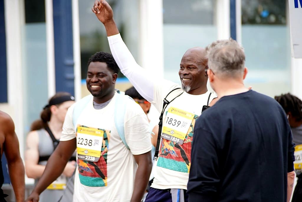 Djimon Hounsou smiling and raising an arm alongside runners at Run Richmond 16.19